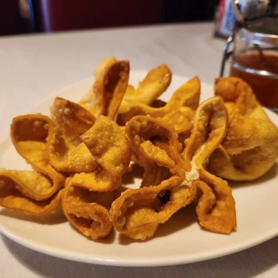 A white plate filled with golden-brown, crispy fried wontons from House of Chou.